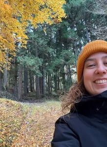 Elisabet Osuna in a yellow beanie taking a selfie in a japanese forest.